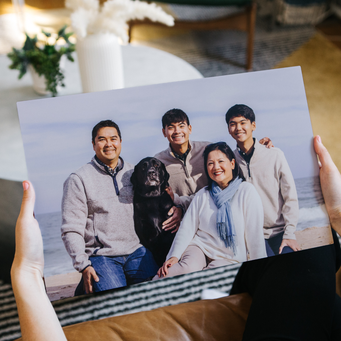 Custom aluminum photo print of a smiling family with dog at the beach, displayed on a sleek metal surface by Aluminyze
