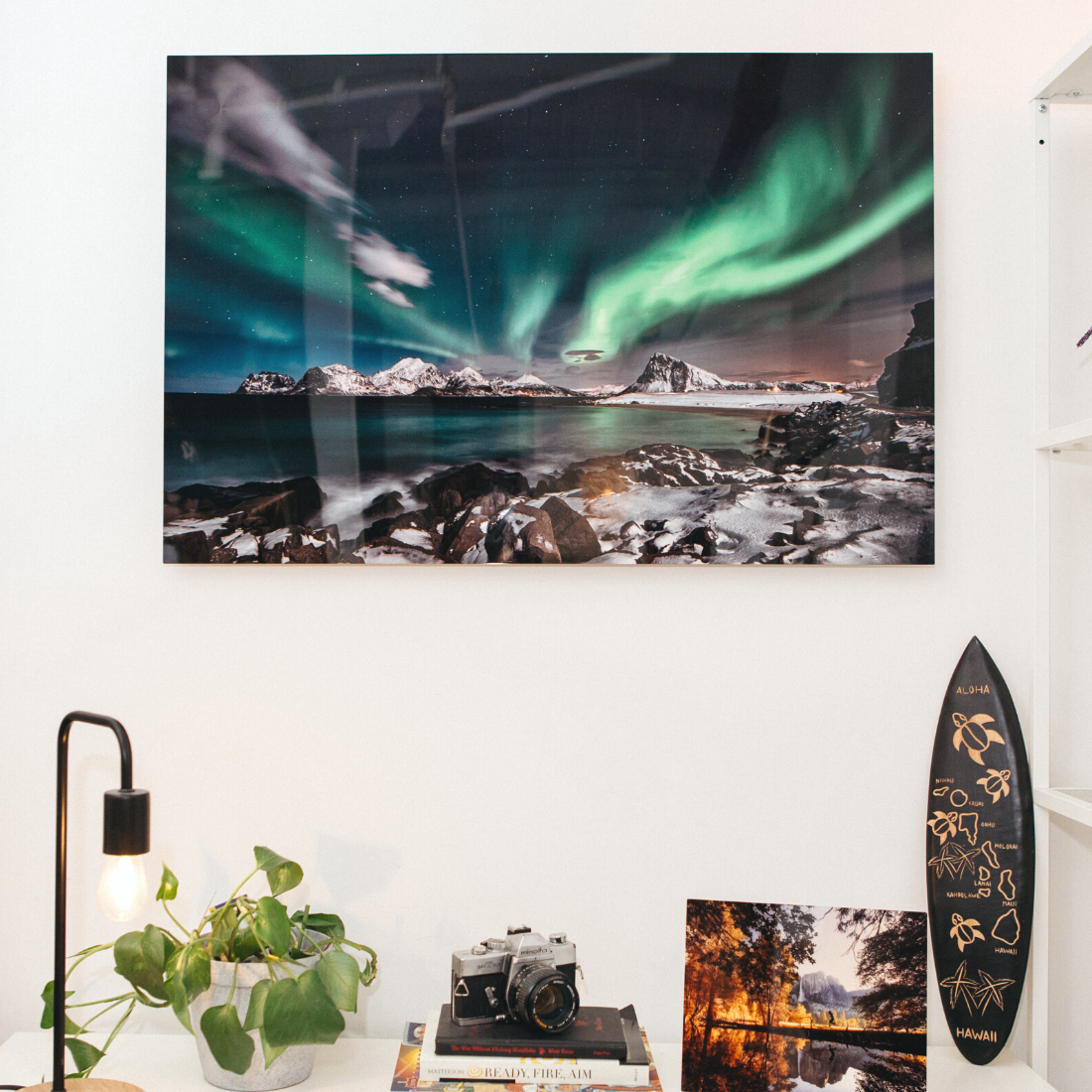 Northern lights metal wall art print featuring a snowy mountain landscape and rocky shoreline, custom aluminum photo panel by Aluminyze