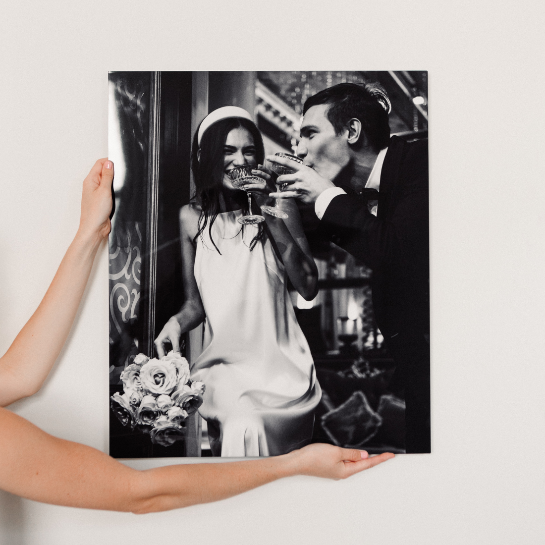Elegant black and white wedding photo printed on metal featuring bride and groom toasting with champagne, premium aluminum wall art by Aluminyze