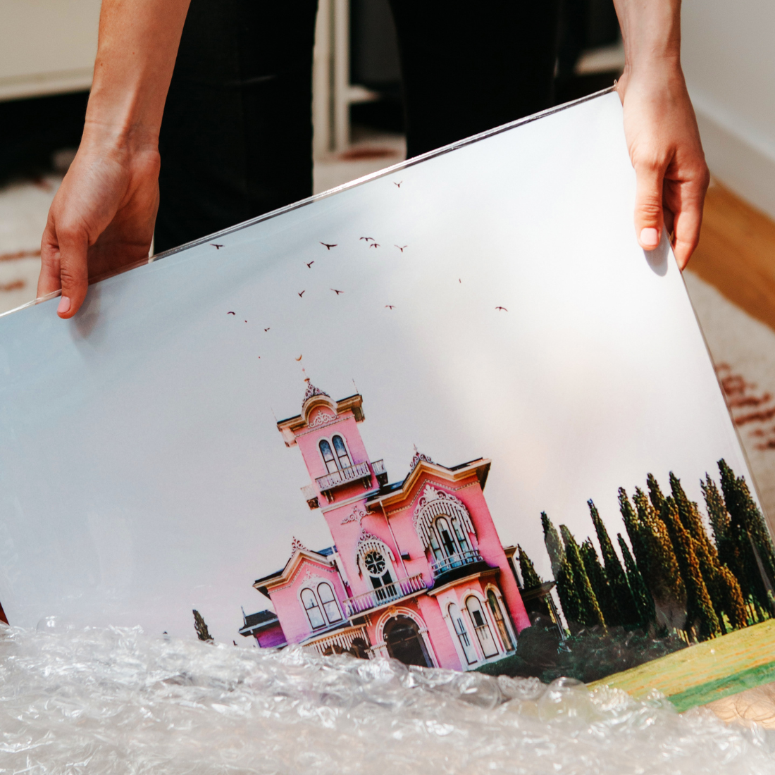 Glossy aluminum print of a vibrant pink Victorian house, unwrapped from protective bubble wrap — a premium photo on aluminum handcrafted by Aluminyze for stunning metal wall art.